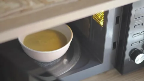 Heating soup in a microwave for quick meal preparation Stock Footage 337752488