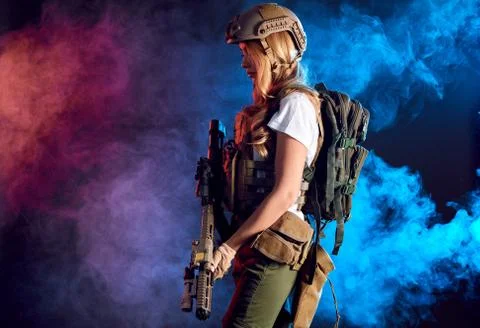 Heavily armed female soldier in battle helmet holding assault rifle Stock Photos