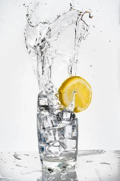 Heavy and large splash of an ice cube in a glass of fizzy drink decorated with a Stock Photos
