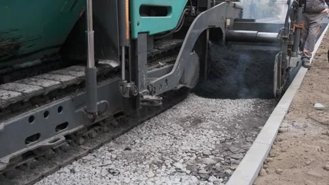 Heavy asphalt paver machine laying hot tarmac on gravel base Stock Footage 339802356