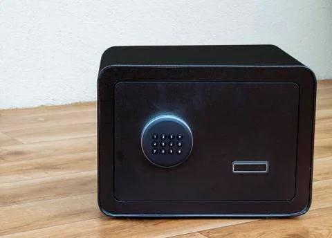 Heavy, black safe with a keypad standing on wooden floor Stock Photos