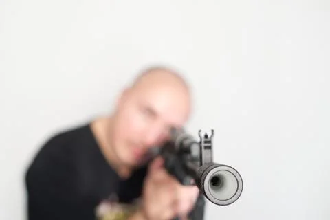 Heavy blurred man on light background with rifle in hands Stock Photos