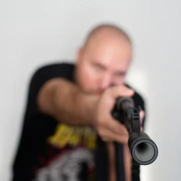 Heavy blurred man on light background with rifle in hands Stock Photos