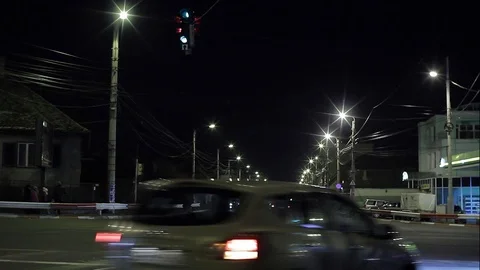 Heavy car traffic at an intersection illuminated by street lamps at night Stock Footage 95797041