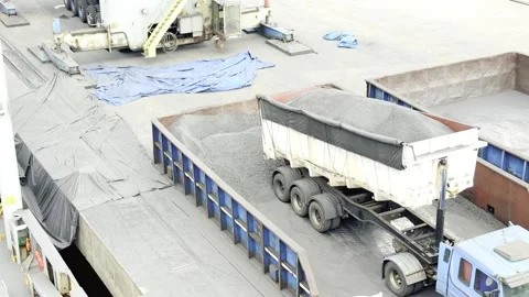 Heavy Clamshell Crane Scooping Petroleum Coke Unloaded by a Red Dump Truck at an Stock Footage 329250883