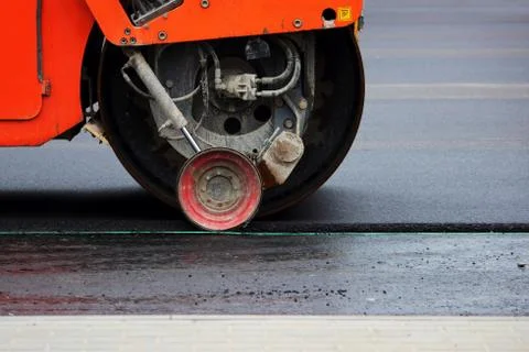 Heavy compactor tires the upper layer of asphalt in the construction of a Stock Photos