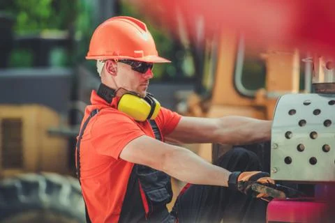 Heavy Construction Equipment Worker Between Machines. Caucasian Men in His 30 Stock Photos