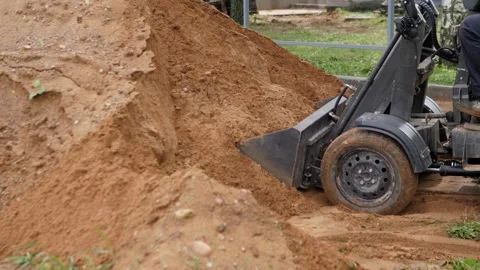 Heavy construction machine pushing loose soil beside grassy worksite, close side Stock Footage 344874225