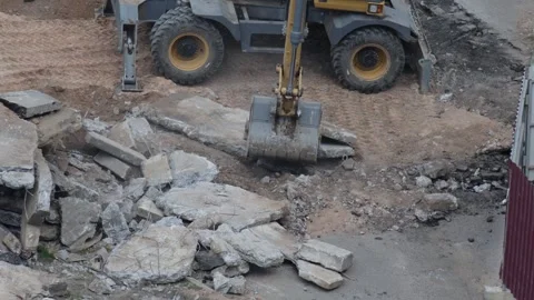 Heavy construction machinery, a backhoe, performs demolition work on concrete Stock Footage 344864036