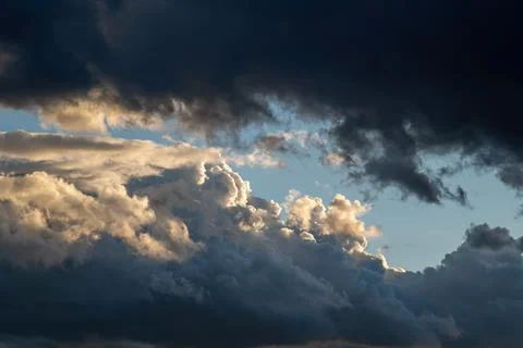 Heavy dark clouds at the sunset. Dramatic sky cloudscape lighted with setting Stock Photos