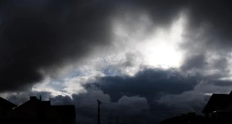 Heavy dark dramatic clouds above the rooftops of houses in the city. 스톡 사진