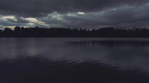 Heavy dark storm clouds move over the pond and are reflected in its surface Stock Footage 61566017