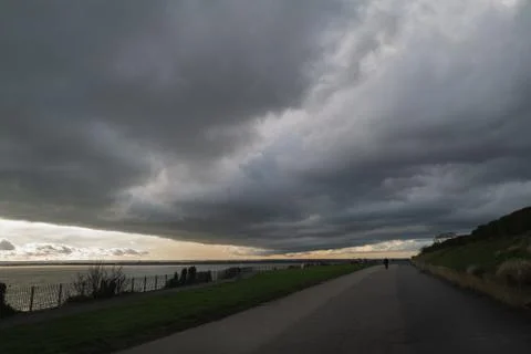 Heavy dark storm clouds over a seaside promenade Stock Photos