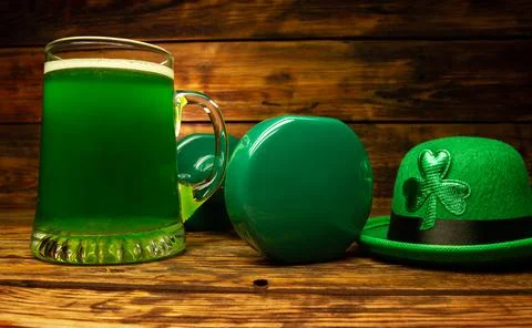 Heavy dumbbell, glass of green beer, Irish hat with shamrock leaf clover. Stock Photos