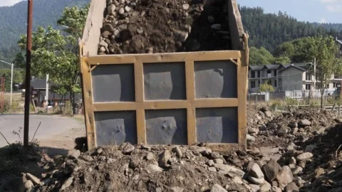 Heavy dump truck unloading soil near residential area in the afternoon Stock-Footage 287376533