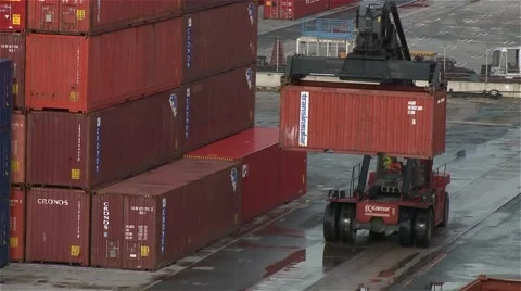 Heavy duty container handler moving shipping containers in harbor  Stockbeeldmateriaal 56973878