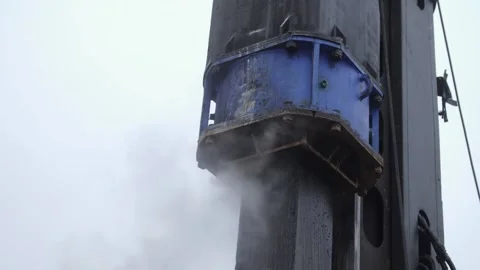 Heavy-duty machine driving concrete pile into ground to provide foundation Stock Footage 158050666