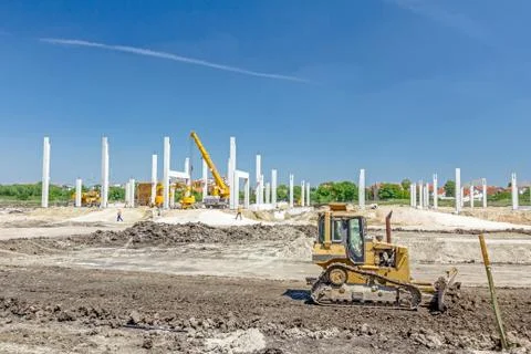 Heavy earthmover construction machine is moving earth at building site Stock Photos