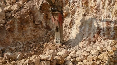 Heavy excavator actively breaking rocks and creating dust in a quarry Видео 312101296