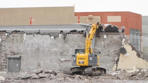 Heavy excavator construction machine destroys wall at demolition site C Stock Footage 125056757