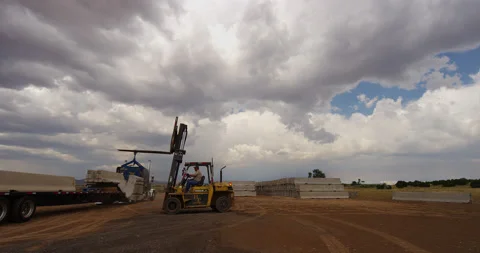 Heavy forklift loading concrete road barriers onto a flatbed trailer in Arizona. Video stock 235104066