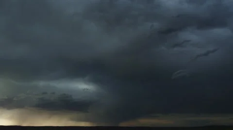 Heavy gray clouds flow across prairie as rain falls along dark horizon, time Stock Footage 59525665