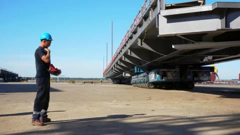 Heavy Industrial worker engineer piloting self propelled modular trailer.  Stock Footage 133627538