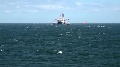 Heavy lift ship sails between motorboats on blue foaming sea Video stock 114262603