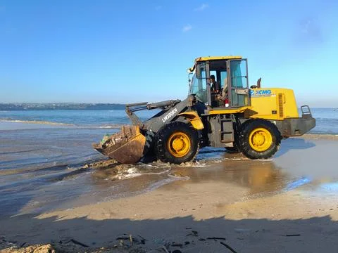 A heavy machine in operation to transport garbage on the beach. Stock Photos