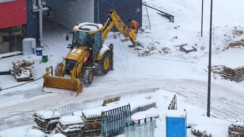 Heavy machinery clears snow at a construction site during winter in a snowy envi Stock Footage 330987584