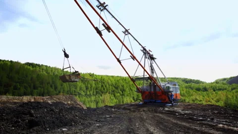 Heavy Machinery Engaged in Mining Operations Set Against a Lush Green Backdrop Stock Footage 282965003