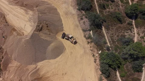Heavy machinery operates in an open-pit sand quarry beside dense vegetation Video stock 341468029