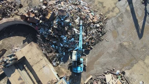 Heavy machinery operates at a scrap yard in a large urban area Stock Footage 306300469