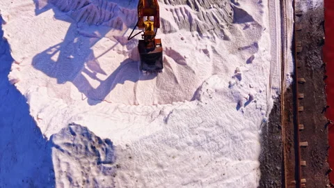 Heavy machinery at work reshaping a snowy landscape by the water in a vibrant Stock Footage 332041455