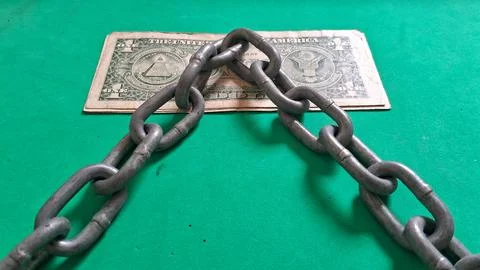 Heavy metal chains resting over a single paper dollar bill Stock Photos