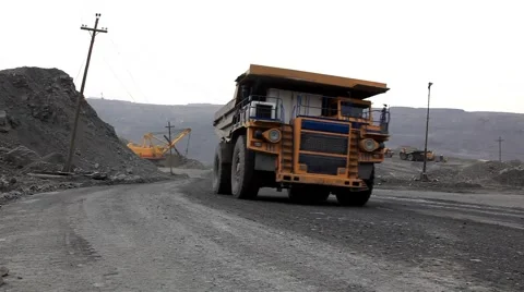 Heavy mining dump trucks driving along the opencast Stock Footage