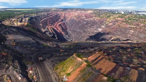 Heavy mining dump trucks driving along dusty haul roads inside vast iron ore Video stock 321641773