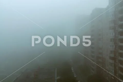 Heavy morning fog and evaporation in the city with high-rise buildings Stock Photos