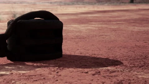 Heavy object resting on dry, cracked ground in barren landscape at sunset Stock Footage 342039875