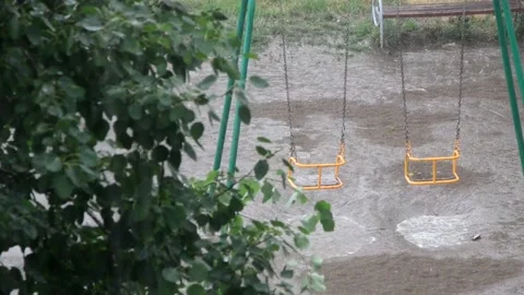 Heavy rain against the tree and a children's playground streams of water Stockbeeldmateriaal 143337819