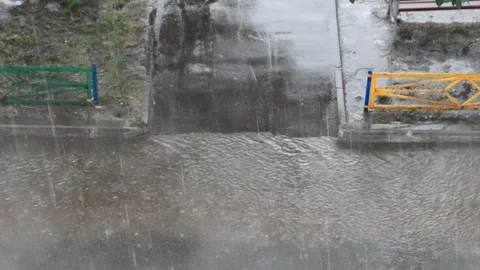 Heavy rain against the tree and a children's playground streams of water Видео 143338103