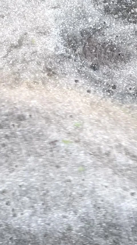 Heavy rain and hail falls on the asphalt. Water flows heavily down the road. Stock Footage 306149573
