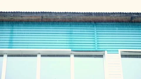 Heavy rain on the background of gray clouds. Heavy rain pours from the roof of Stock Footage 231536692