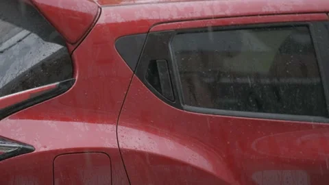 Heavy rain drips on the background of a red car. Close up. Stock Footage 130546414