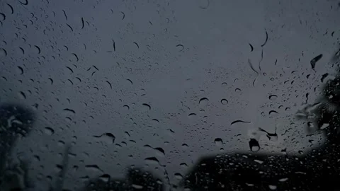 Heavy rain drops falling on a car windshield at dusk. Stock Footage 343872958