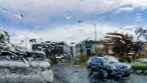 Heavy rain drops falling externally on vehicle windscreen Stock Photos