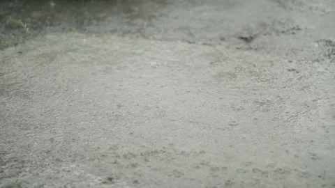 Heavy rain drops falling on a large puddle on concrete ground Stock Footage 338364441