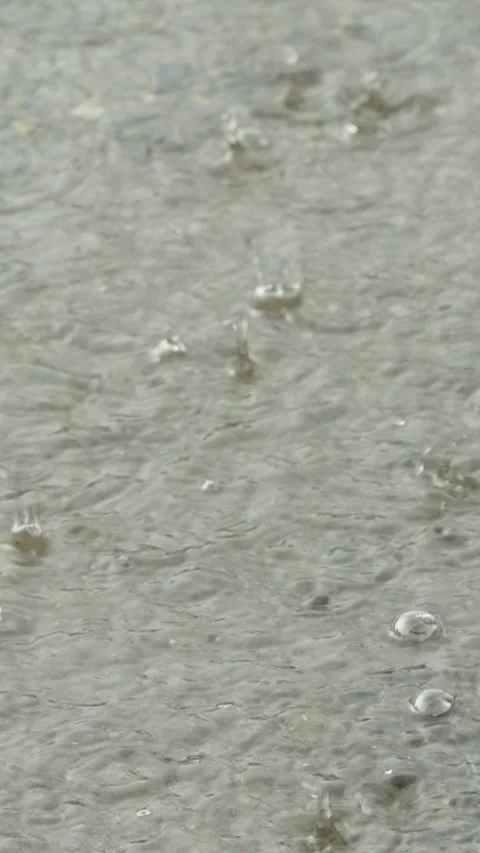 Heavy rain drops falling on a large puddle on concrete ground Stock Footage 338364975