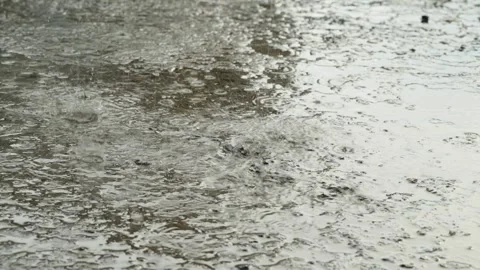 Heavy rain drops falling on a large puddle on concrete ground Stock Footage 338365076