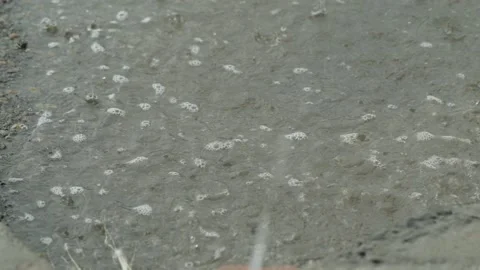 Heavy rain drops falling on a large puddle on concrete ground Video stock 338365274